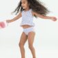 Child in floral swimsuit holding a pink bucket