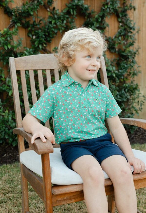 Child sitting on wooden chair outside smiling.