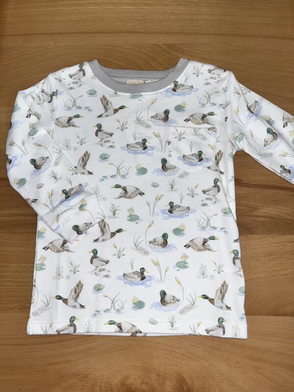 Duck print toddler shirt on wooden surface.