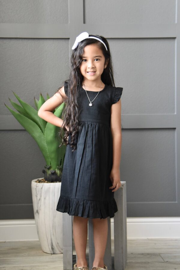 yo baby black angel sleeves shift dress Girl in black dress with plant background.