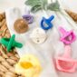 Colorful baby pacifiers on a woven basket.