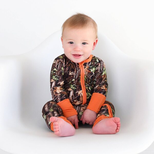 gigi and max hunter camo zip sleepies little bamboo baby outfit Baby in camo pajamas sitting and smiling.