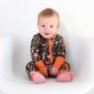 Baby in camo pajamas sitting and smiling.