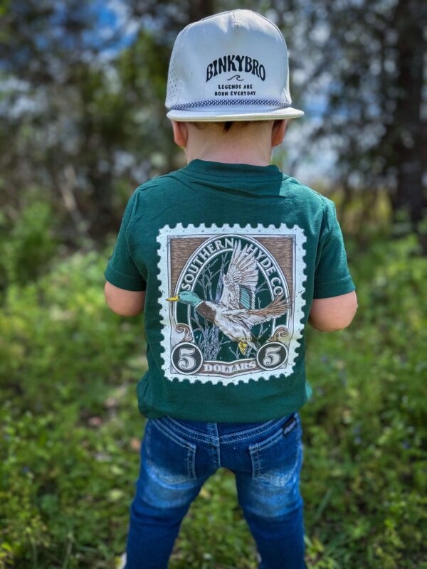Child in green shirt and cap outdoors.