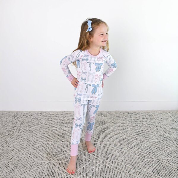 gigi and max samantha bows two piece no button bamboo kids lounge Child wearing bow-patterned pajamas smiling.