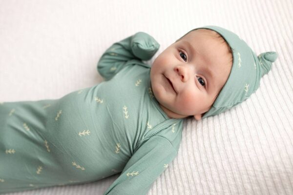 three little tots arrow print knotted newborn baby gown pajamas Smiling baby in green outfit on blanket.