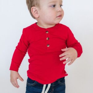 Toddler in red shirt and jeans looking sideways.