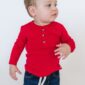 Toddler in red shirt and jeans looking sideways.