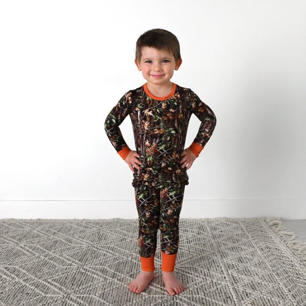 gigi and max hunter camo two piece no button bamboo outfit lounge Child in camo pajamas smiling on rug