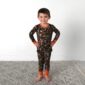 Child in camo pajamas smiling on rug