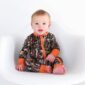 Baby in camouflage onesie on white chair.