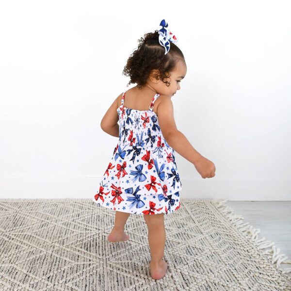 gigi and max eleanor bow clip bow 4th of july hair accessory Toddler in butterfly dress, walking on rug.