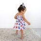 Toddler in butterfly dress, walking on rug.