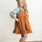 Child in blue floral and brown dress posing