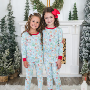 Children in Christmas pajamas by fireplace and wreath.