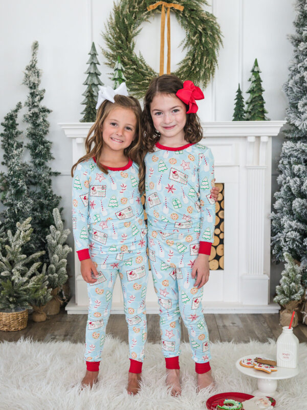 Children in Christmas pajamas by fireplace and wreath.