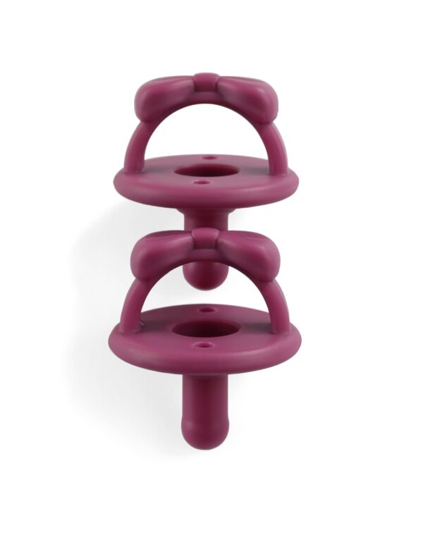itzy ritzy sweetie soother™ pacifier sets (2 pack): aquamarine + peach bows Two purple baby pacifiers with bow designs.