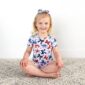 Child in butterfly outfit sitting on rug, smiling.