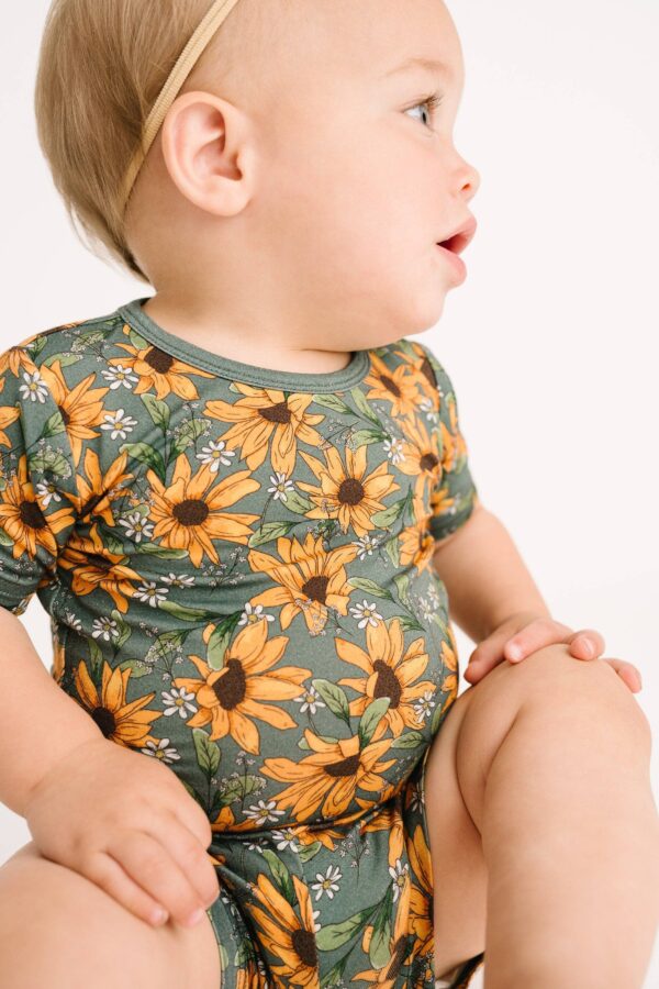 little one shop sunflower meadow bamboo shorts set Baby in sunflower-patterned outfit sitting sideways.