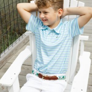 Smiling boy sitting on white chair outdoors.