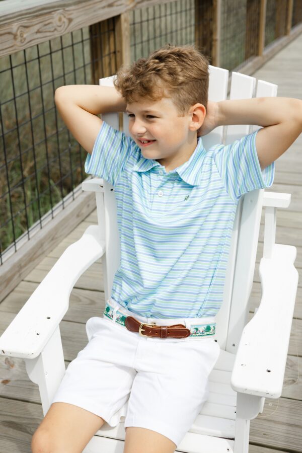 j. bailey perfromance polo island Smiling boy sitting on white chair outdoors.