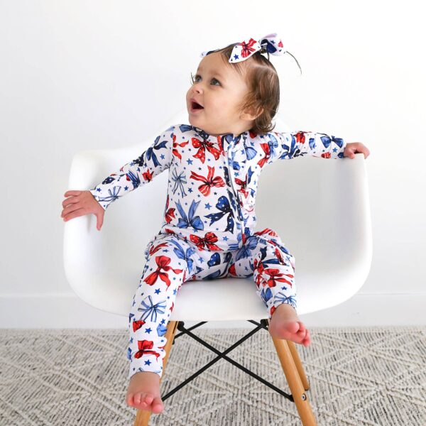 gigi and max eleanor bow clip bow 4th of july hair accessory Baby in patterned pajamas and headband on chair.