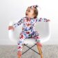 Baby in patterned pajamas and headband on chair.