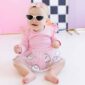 Baby wearing pink outfit and sunglasses, smiling.