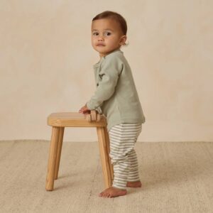 Toddler standing with a wooden stool.