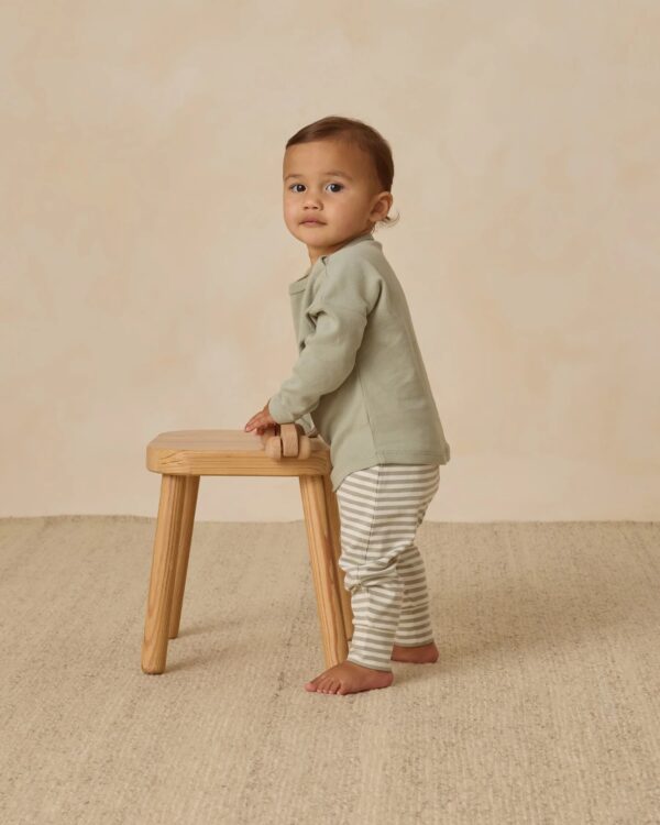 Toddler standing with a wooden stool.