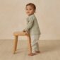 Toddler standing with a wooden stool.