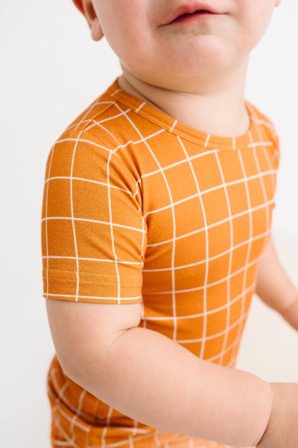little one shop rust checks bamboo shorts set Baby in orange grid-patterned shirt, close-up.
