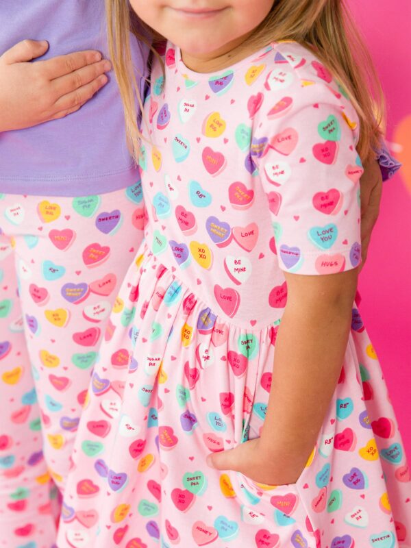 rufflebutts + ruggedbutts girls be my valentine short sleeve knit twirl dress Children's heart-patterned clothing on pink background.