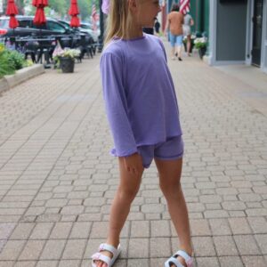 Child in purple outfit on a city street.