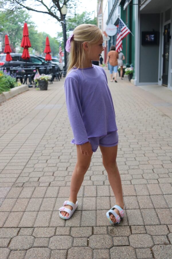 Child in purple outfit on a city street.