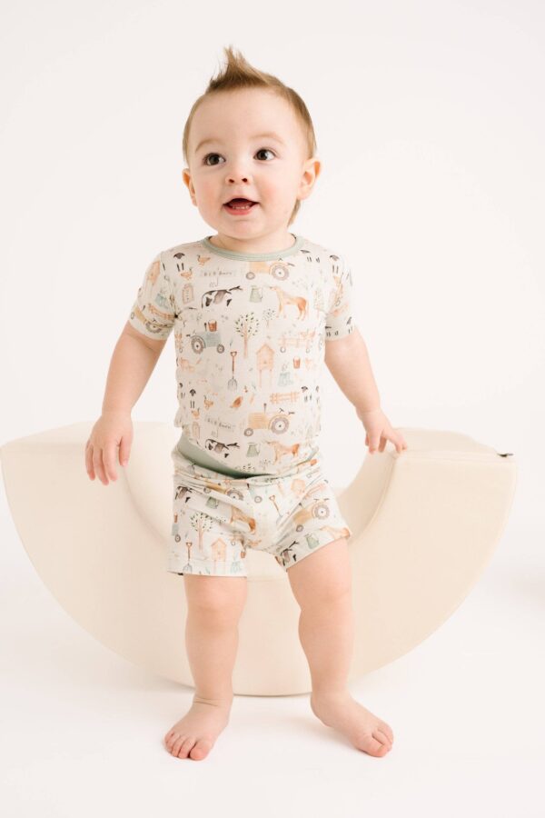 little one shop little farm bamboo shorts set Baby wearing farm-themed pajamas on rocking chair.