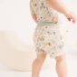 Toddler wearing patterned outfit, walking indoors.