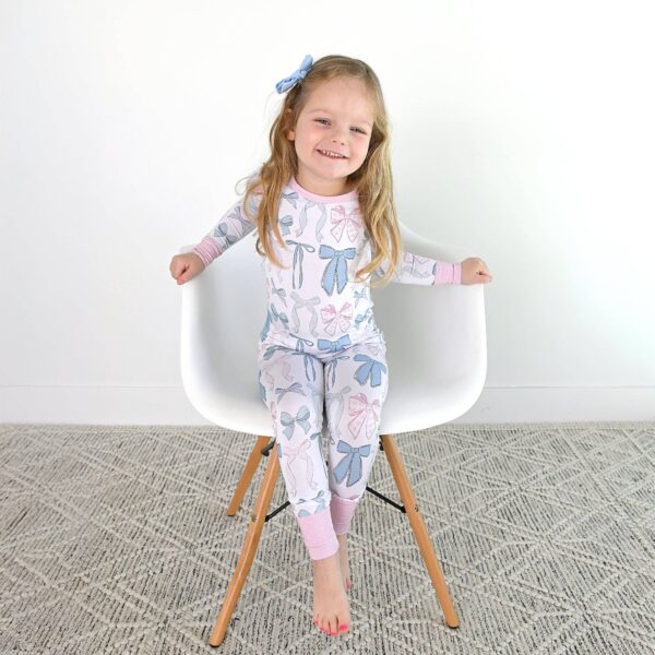 gigi and max samantha bows two piece no button bamboo kids lounge Smiling child in pajamas sitting on chair.