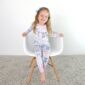 Smiling child in pajamas sitting on chair.