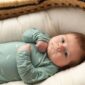 Baby in green outfit lying in crib