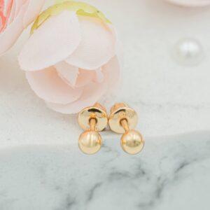 Gold stud earrings on marble with pink flowers.