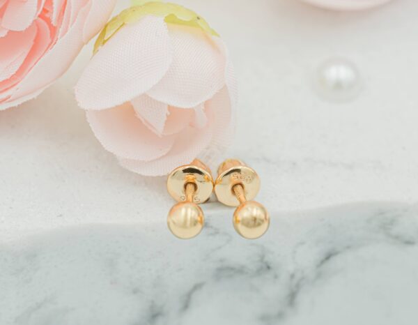 cherished moments 14k gold plated ball stud earrings for baby & kids Gold stud earrings on marble with pink flowers.