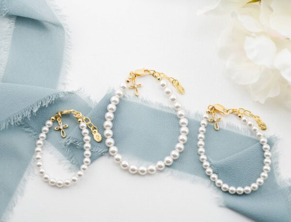cherished moments kids14k gold plated baptism cross bracelet or communion gift Elegant pearl bracelets on blue ribbon with flowers.