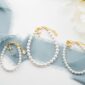 Elegant pearl bracelets on blue ribbon with flowers.