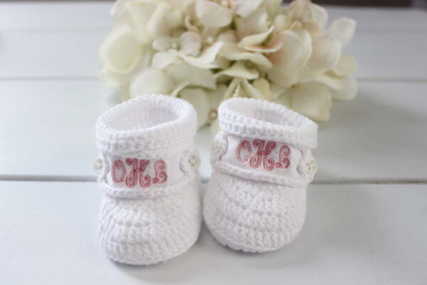 White knitted baby booties with monogrammed initials