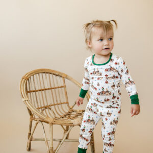 Child in patterned pajamas near wicker chair.