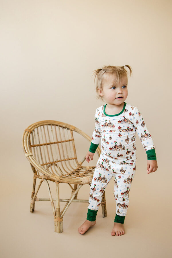 Child in patterned pajamas near wicker chair.