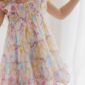 Child in colorful floral dress, smiling indoors.