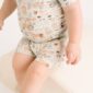 Baby wearing farm-themed pajama set, sitting on white.