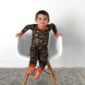 Child in camouflage pajamas on white chair